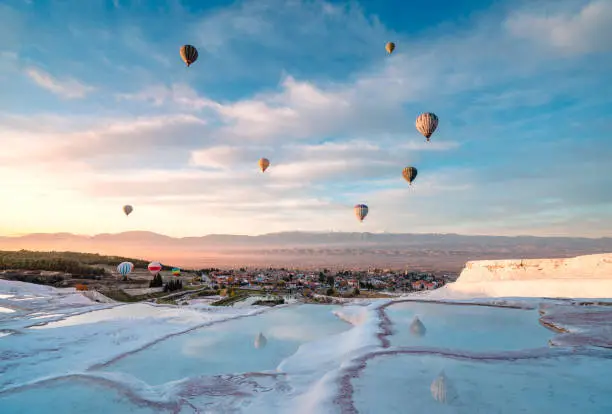 Photo of Hot air balloons in travertine pools limestone terraces at sunrise in Pamukkale, Denizli
