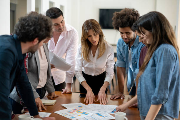istock Diverse team of people paying attention to female boss while explaining something all looking at a document during a meeting 1194918029