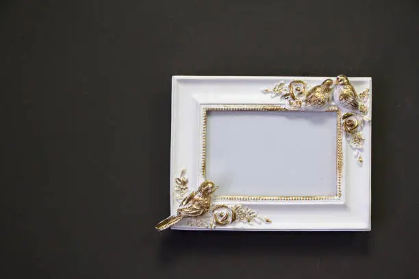 Empty white gold vintage square frame in Victorian style on a gray wall, background or concept