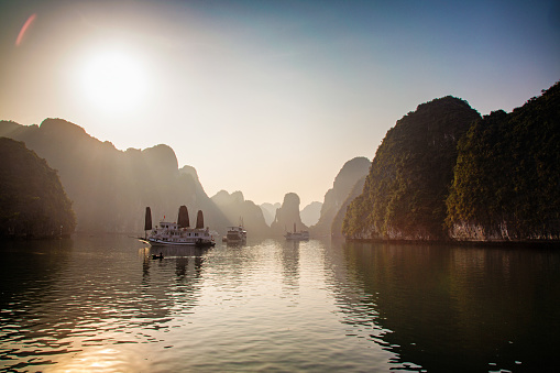Misty dawn on Halong Bay Vietnam wide angle panoramic view with tourist boats.