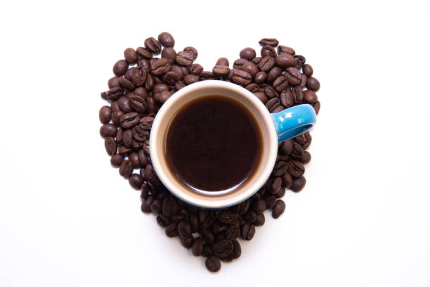 forma de corazón creada con granos de café y una taza - endosperm fotografías e imágenes de stock