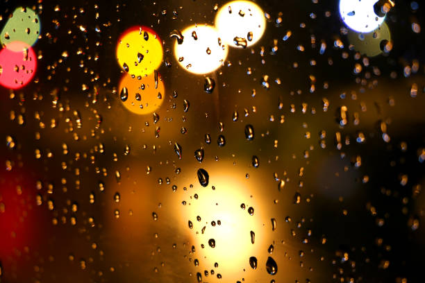 istock Rain droplets on glass at night 1194921654