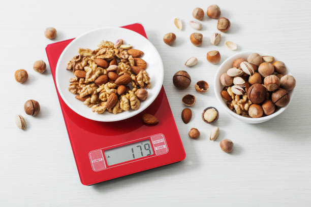 mix of different nuts on  kitchen scale on a white table stock photo