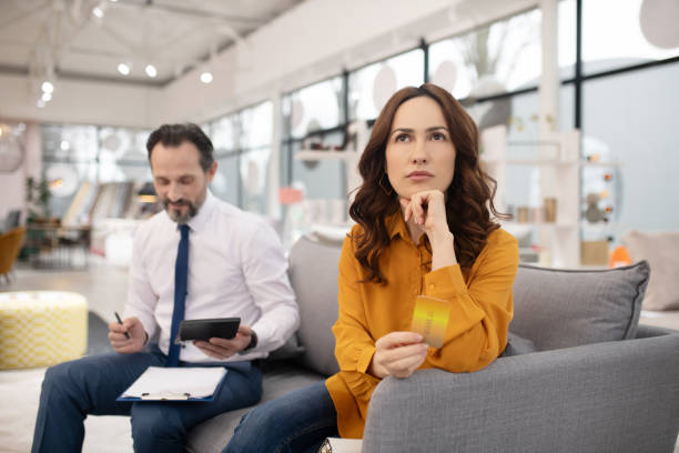 istock Dark-haired pretty customer in yellow shirt looking thoughtful 1194921887