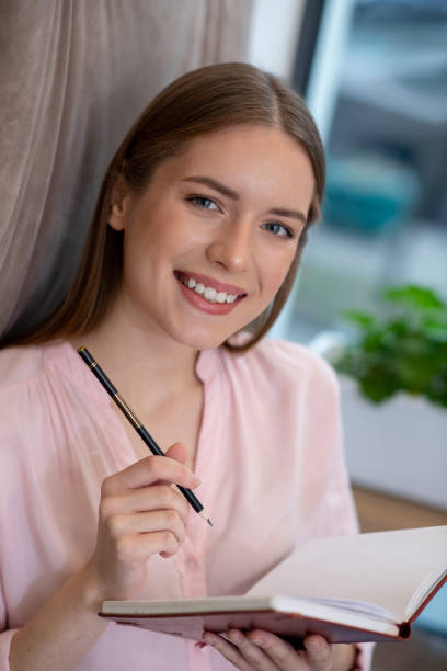 istock Smiling young and creative woman writing ideas in her notebook 1194922953