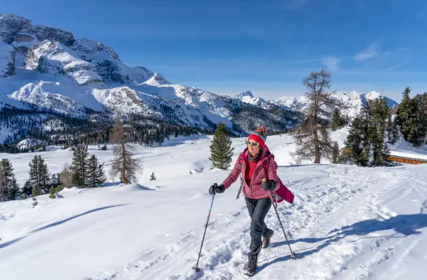 active senior woman snowshoeing from Prato Piazzo up to the Monte Specie in the three peaks Dolomites area near village of Innichen, South Tyrol, Italy