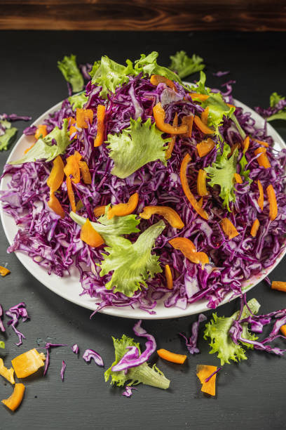 istock head lettuce bell pepper red cabbage salad casually scattered around a flat dish black bacround. vertical. 1194925193