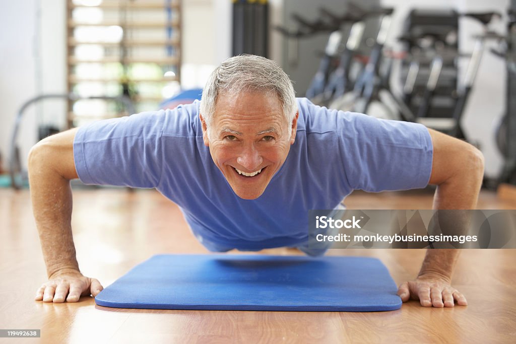 Senior hombre haciendo prensa Ups en el gimnasio - Foto de stock de Tercera edad libre de derechos