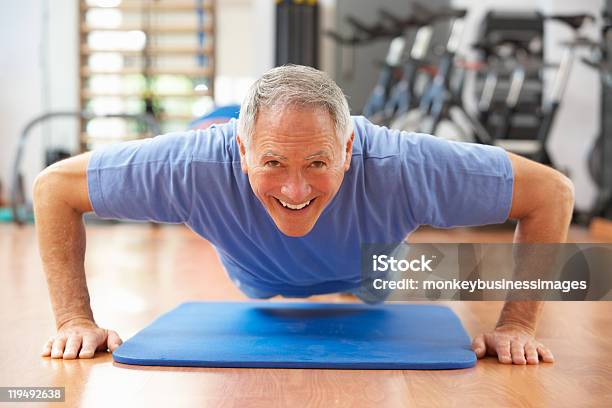 Senior Hombre Haciendo Prensa Ups En El Gimnasio Foto de stock y más banco de imágenes de Tercera edad - Tercera edad, Hombres mayores, Flexiones