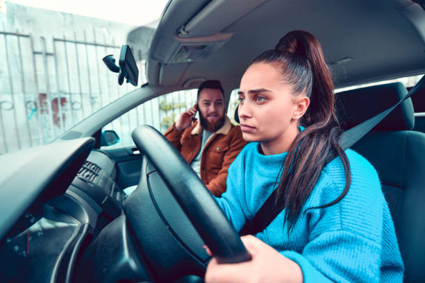 istock Male Talking On Phone While Inexperienced Female Driver Struggles With Car 1194926623