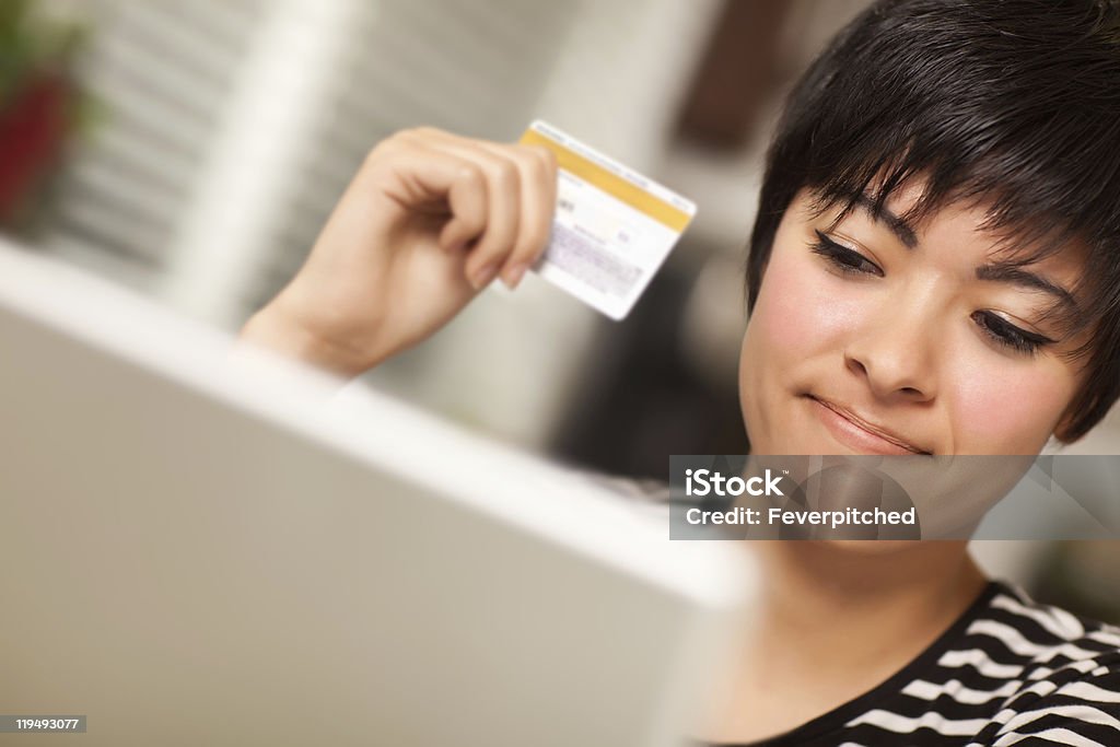 Étnica sorridente Mulher segurando o cartão de crédito usando computador portátil - Royalty-free Adulto Foto de stock