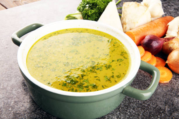 istock Broth with carrots, onions various fresh vegetables in a pot - colorful fresh clear spring soup. Rural kitchen scenery vegetarian bouillon stock 1194932091