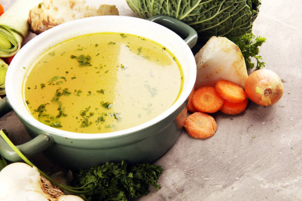 istock Broth with carrots, onions various fresh vegetables in a pot - colorful fresh clear spring soup. Rural kitchen scenery vegetarian bouillon stock 1194932380