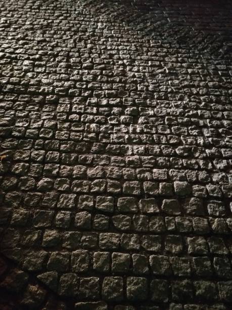 istock Street, cobblestone road in car lights 1194944347