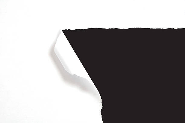 A torn white piece of paper revealing a black background stock photo