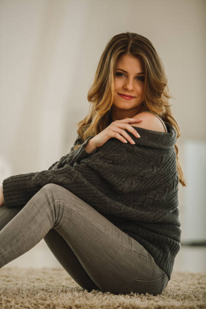 istock Confident young woman sitting on the floor and smiling while looking at camera 1194956085