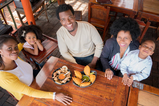 la familia afro comienza a comer las empanadas y las cortezas de cerdo que traen a la mesa del restaurante