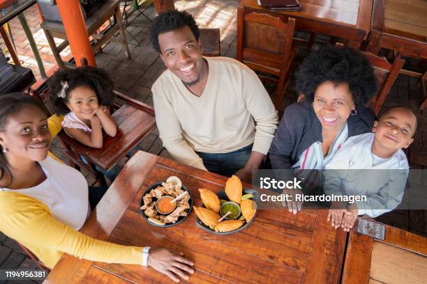 The Afro Family Begins To Eat The Empanadas And The Pork Rinds They Bring To The Restaurant Table Stock Photo - Download Image Now