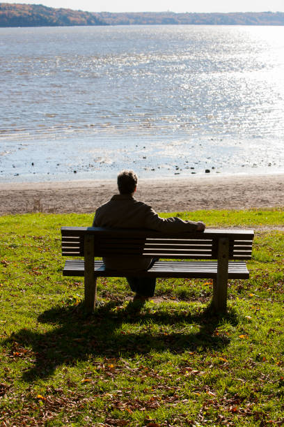 istock Mature man sitting on bench overlooking River in Autumn. 1194960251