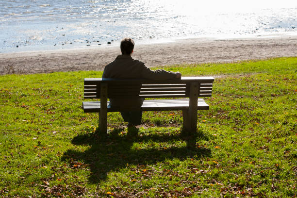 istock Mature man sitting on bench overlooking River in Autumn. 1194960305