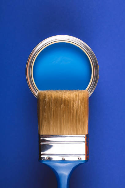 istock Brush on open can of blue paint on blue background. 1194961186