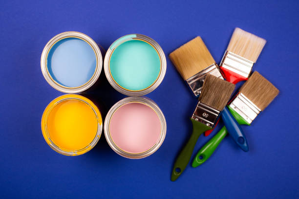 istock Four open cans of paint with brushes on bright background. 1194961193