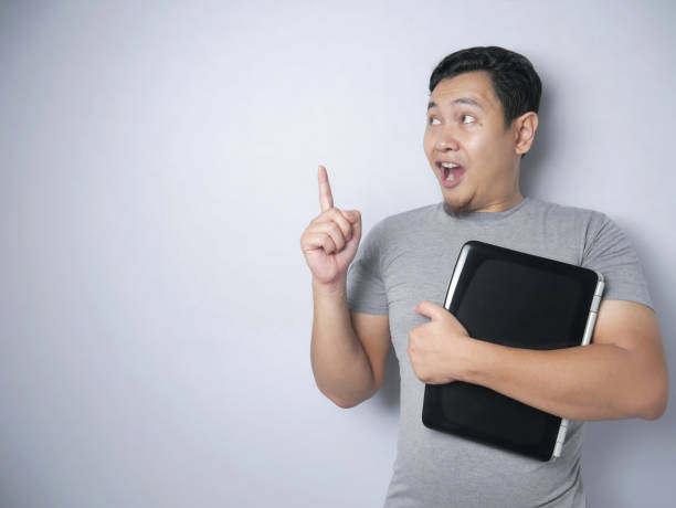 istock Funny Asian Man Holding Laptop, Thinking and Smiling For Having Good Idea 1194961481