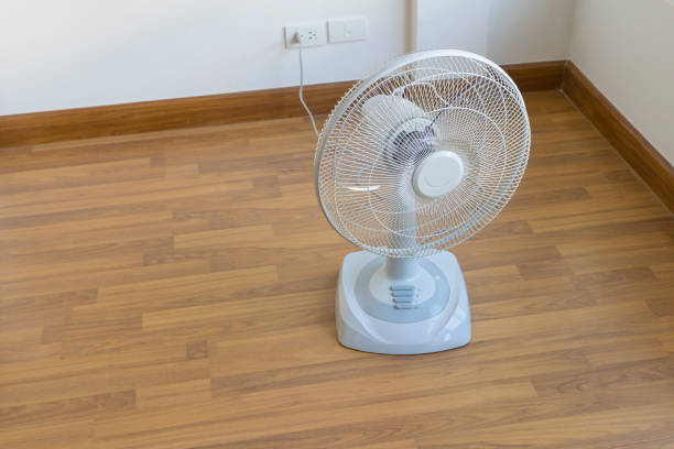 Table electric fan sit on the wooden floor of the house.