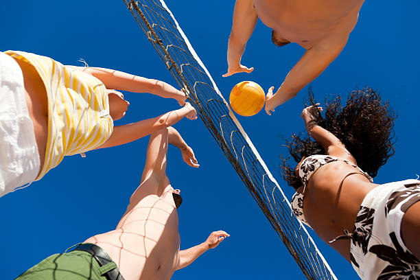 voleibol de playa de juego en la red - vóleibol de playa fotografías e imágenes de stock