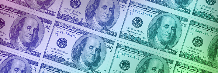 Close-up of $100 US dollar banknotes with a purple - green color gradient. Can be used as a background for your projects.