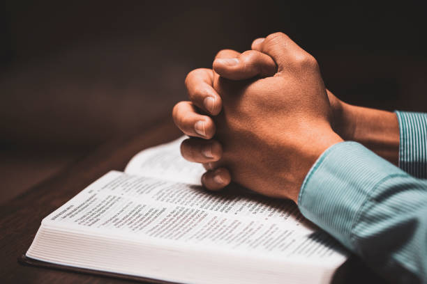 istock Man praying with his hands on a bible 1194993314