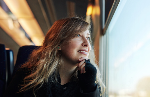Cropped shot of an attractive young woman sitting alone on a train and looking out the window during her commute