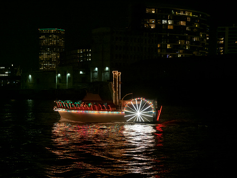 Portland, Oregon, USA - December 17, 2019: A boat decorated as a Sternwheeler for The Christmas Ship Parade on the Willamette River. Downtown Portland Oregon is seen in the background. 2019 is the 65th year of the parade. It goes on the Columbia and Willamette River. This year it will run for 15 nights.