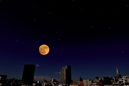 Full moon rising over the buildings and lots of stars with copy space.