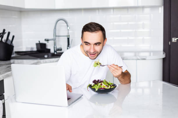 istock Portrait of handsome man have breakfast while use laptop in white kitchen. 1195002733