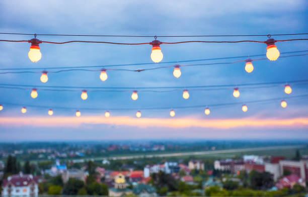 istock several rows of decorative outdoor light strings hanging on cityscape background at twilight 1195003593