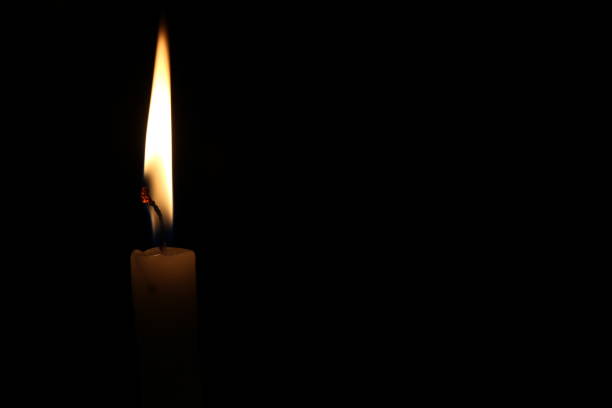 istock One light candle burning brightly in the black background 1195006623