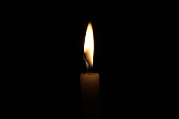 istock One light candle burning brightly in the black background 1195006624