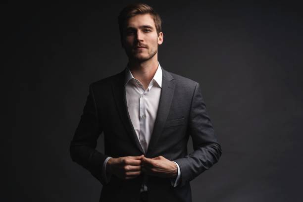 istock Portrait of serious handsome man in gray suit buttoning jacket 1195007229