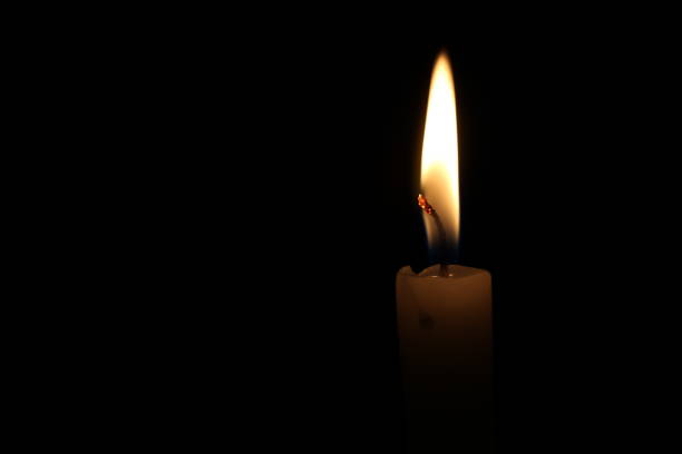 istock One light candle burning brightly in the black background 1195007232