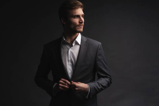 istock Portrait of serious handsome man in gray suit buttoning jacket 1195007251