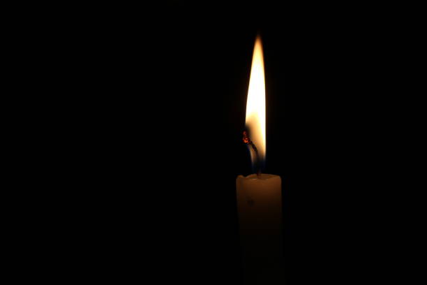 istock One light candle burning brightly in the black background 1195007379