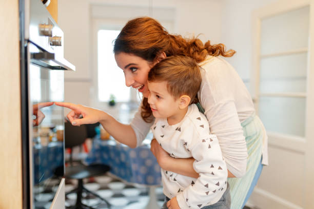 istock Mother and son watching cookies in oven 1195007759