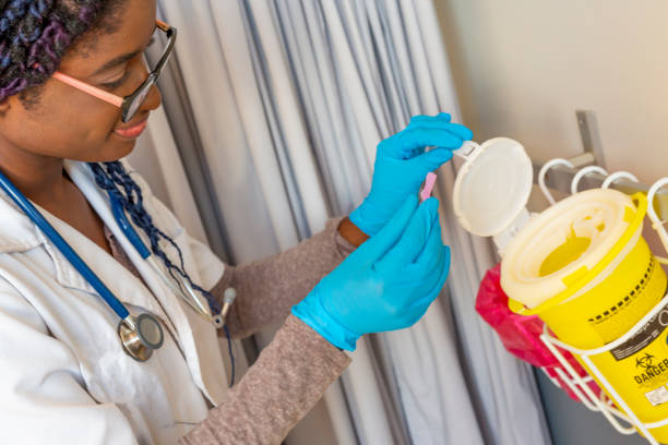 Female Doctor Safely Disposing of Sharp Waste Female Doctor Safely Disposing of Sharp Waste medical alarm stock pictures, royalty-free photos & images