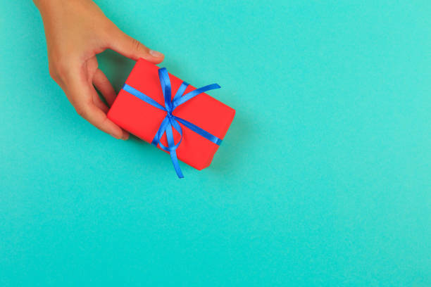 istock gift in female hands on a colored background top view. 1195008906
