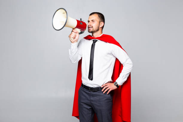 istock Businessman dressed like superhero shouting by megaphone isolated on white background 1195008947