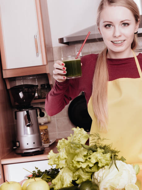 istock Woman in kitchen holding vegetable smoothie juice 1195009510