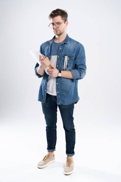 istock Happy young student standing full length with books and notes isolated on white background. 1195011290