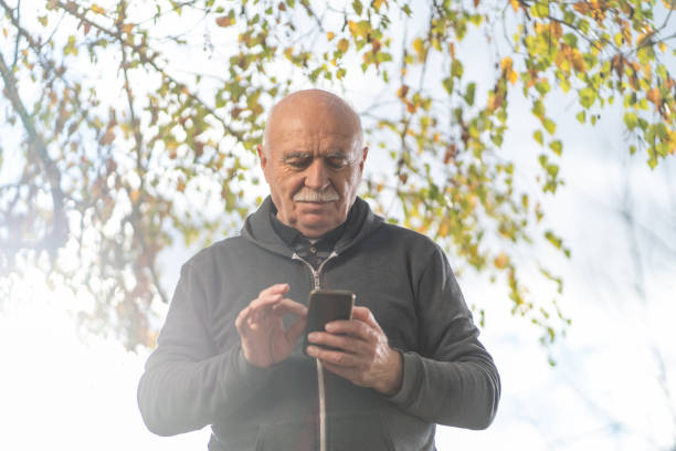 istock Senior man standing in front yard and using phone 1195013549