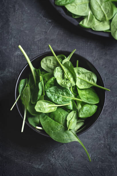 istock Fresh spinach leaves on a dark textured background 1195014499